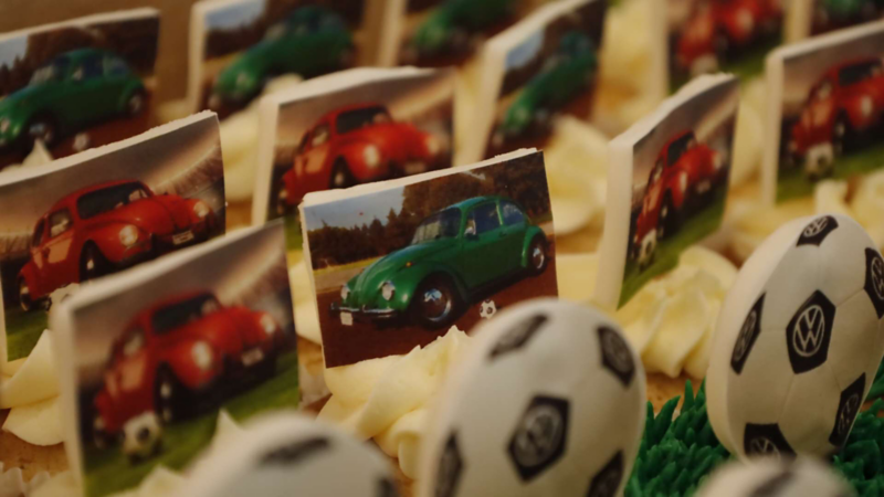 Cupcakes decorados con imágenes de Vochos de color verde y balones con logo VW.