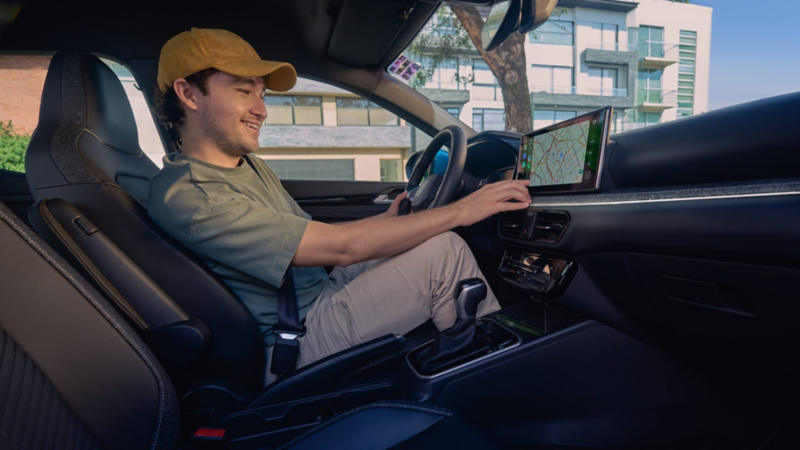 Conductor sonriente utiliza sistema de navegación en pantalla táctil de un SUVW.