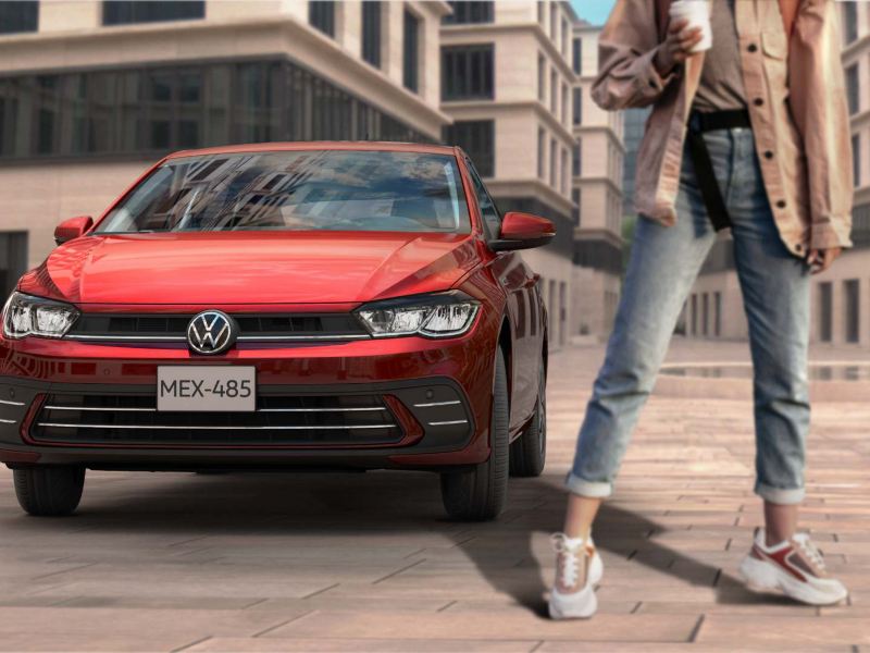 Mujer posa frente a un auto Polo Volkswagen de color rojo. 