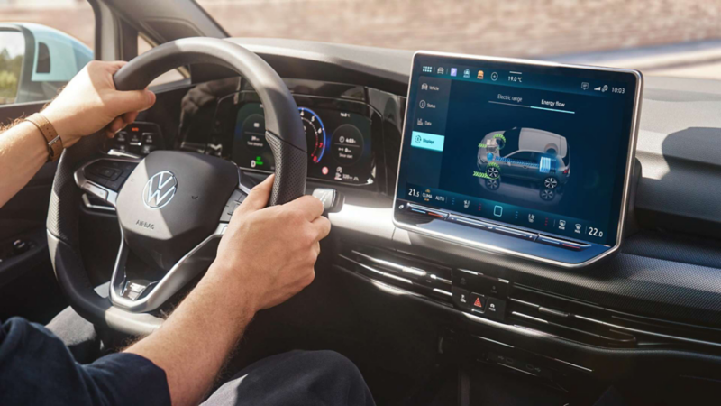 Persona al volante de un Volkswagen mientras la pantalla muestra el flujo de energía del vehículo.