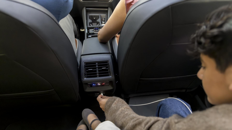 Niño conecta cable a entrada tipo C para cargar dispostivo móvil en Tiguan 2025. 