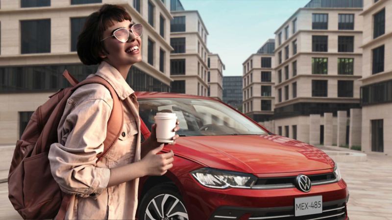 Joven con café en las manos sonríe frente a Volkswagen Polo 2024.