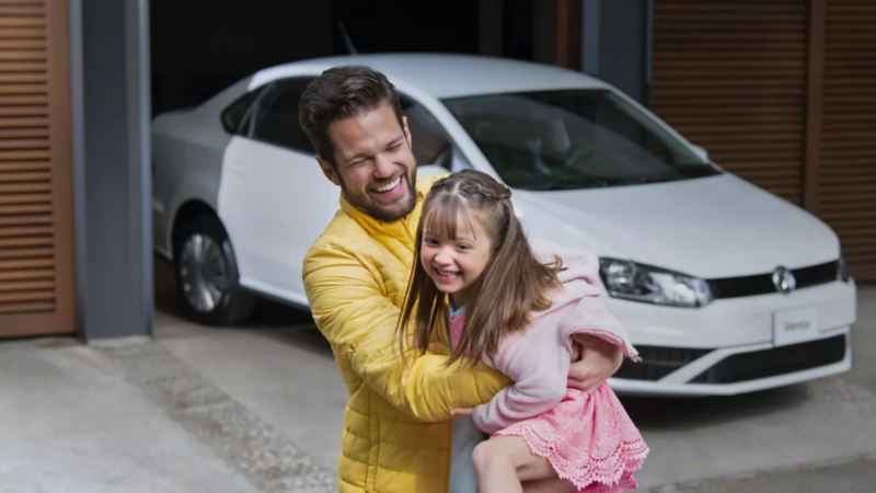 Padre e hija recargados frente a Vento, sedán familiar de Volkswagen disponible en concesionarios VW