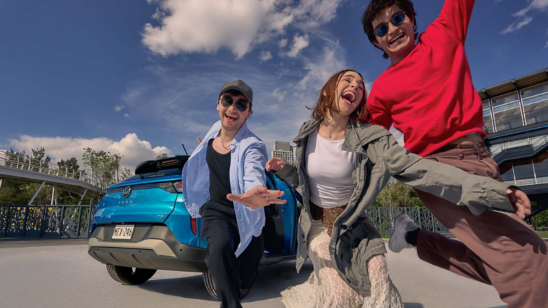Jóvenes sonríen y bailan frente a un Volkswagen Tera 2026 de color azul. 