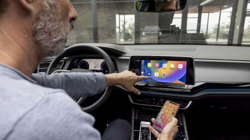 Conductor de camioneta de lujo de Volkswagen conecta su celular a la pantalla semiflotante.