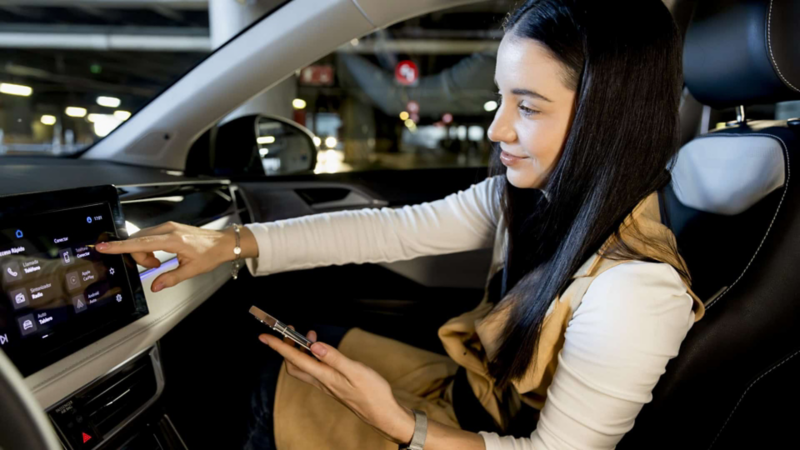 Nuevo Taos 2025. Mujer sentada en el asiento de copiloto toca la pantalla touch semiflotante de camioneta SUV. 