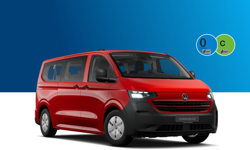 Una Caravelle de ocasión de Volkswagen con las etiquetas de la DGT sobre un fondo azul y blanco