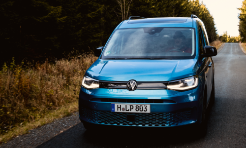 Une voiture Volkswagen roule sur une route de campagne dans les montagnes enneigées