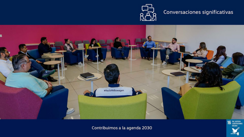 Colaboradores de Volkswagen dialogan en círculo en sala de juntas.	