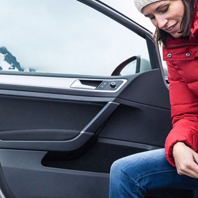 Une femme s'apprêtant à conduire sa Volkswagen, lien vers la page « cout utilisation » de VW