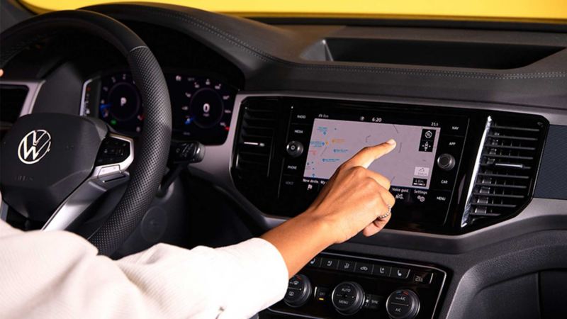 Interior de auto Volkswagen con conductora tocando la pantalla touch. 