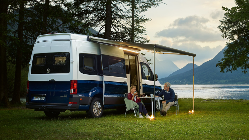 Un uomo e una donna siedono al tavolo sotto la tenda del camper Grand California