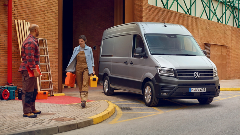 Zwei Handwerker mit Werkzeug neben einem VW Crafter.
