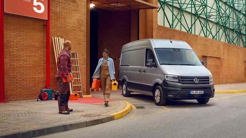 Zwei Handwerker neben dem neuen VW Crafter Kastenwagen.