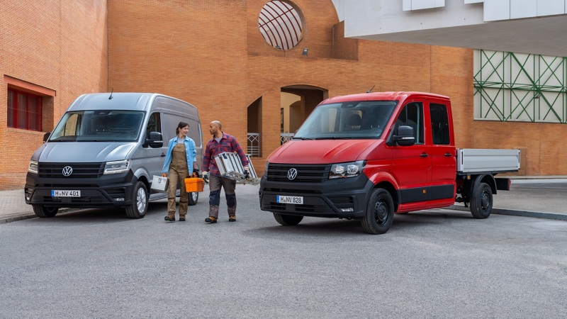 Ein Crafter Kastenwagen und Crafter Pritschenwagen parken vor einem modernen Gebäude.