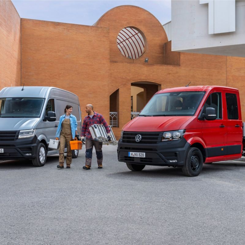 Ένα VW Crafter Van και ένα VW Crafter Pick up. Δύο επαγγελματίες μπροστά του μεταφέρουν εργαλεία.