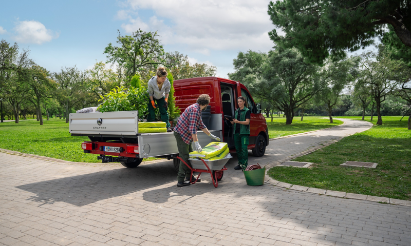 Tres trabajadores descargando materiales de la parte trasera de un VW Crafter Caja Abierta