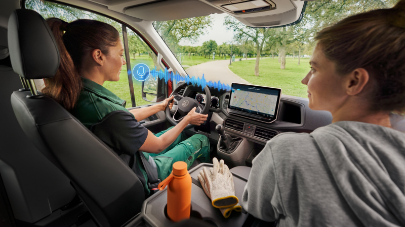 Zwei Frauen sitzen in einem VW und bedienen den IDA-Sprachassistenten.