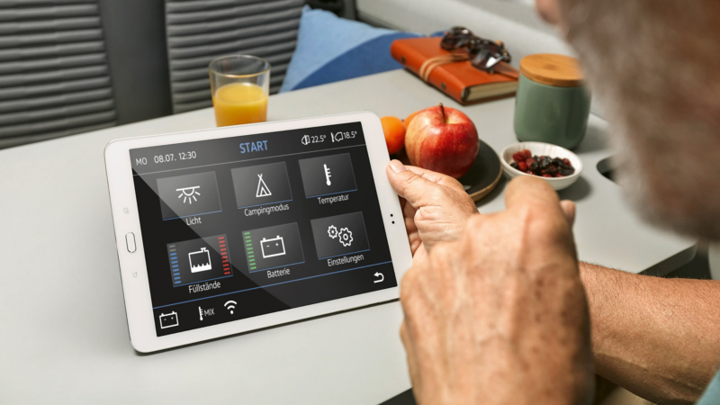 We see two male hands holding a tablet. It shows important vehicle options, such as the temperature, fill level of the water tank and battery charge level. 