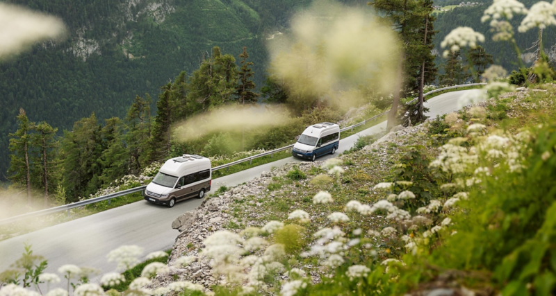 Zwei Grand California fahren auf einem grünen Bergpass.