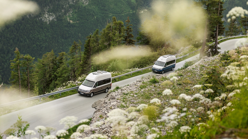 Two VW Grand Californias driving through a mountain landscape.