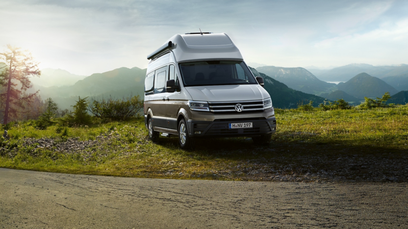 VW Grand California parkt neben einer Straße auf einem Berg.