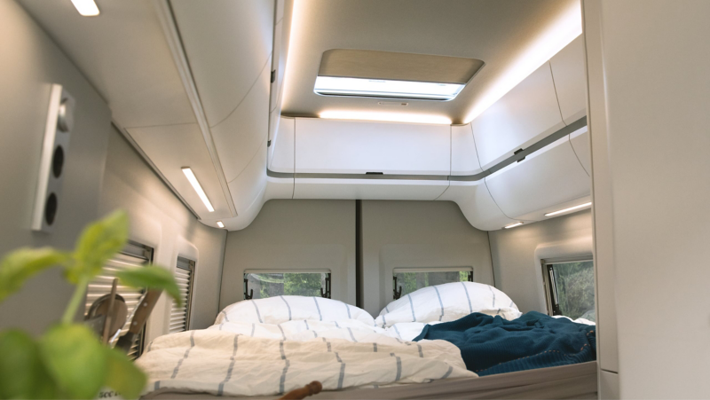 Picture shows the bed in the Grand California 680 with cosy interior lighting. 