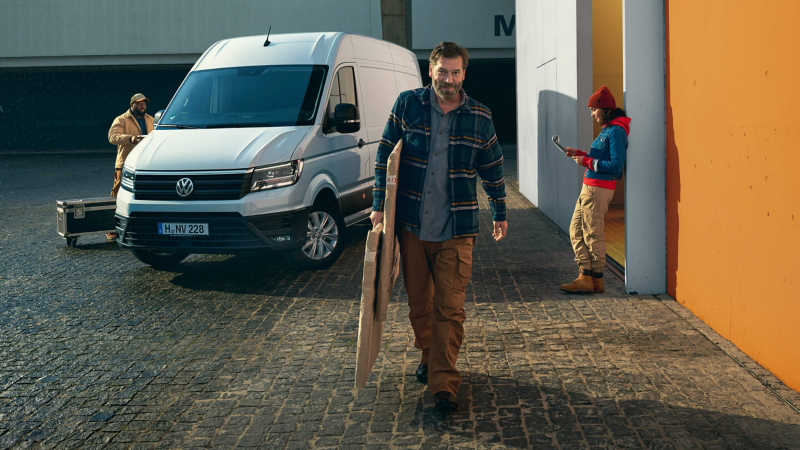 A craftsman unloads wooden slats from a VW Crafter with shelving.