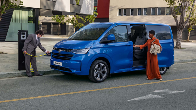 a man plugs a blue eHybrid Transporter Shuttle into a public charging station