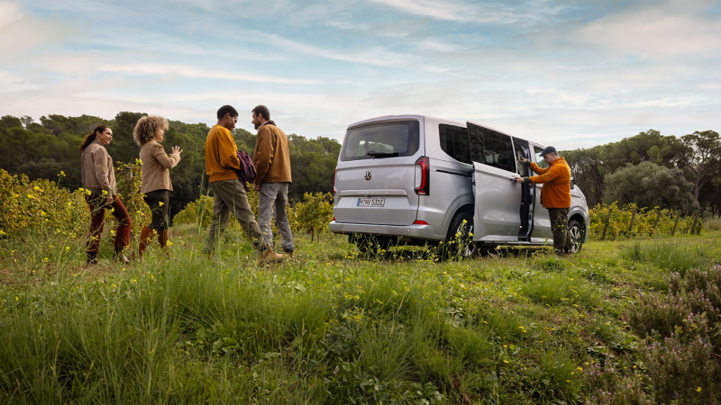 Eine Mann schließt die Schiebetür eines VW Caravelle.
