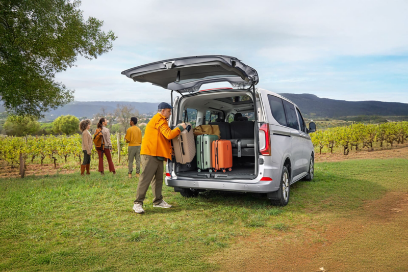 Mężczyzna pakuje walizki do bagażnika Volkswagena Caravelle.