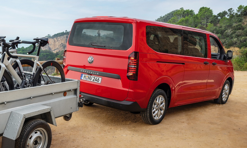 The VW Caravelle is parked with a trailer on a side of the road.