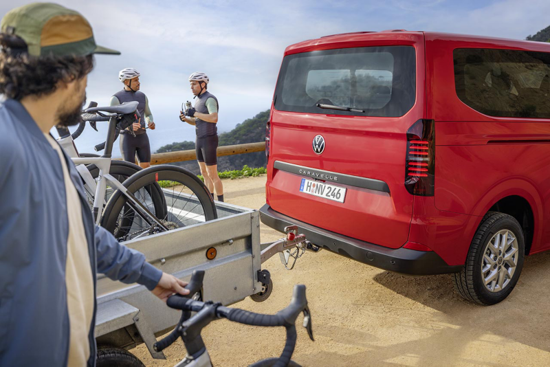 Nueva Caravelle roja aparcada a un lado de la calzada con ciclistas