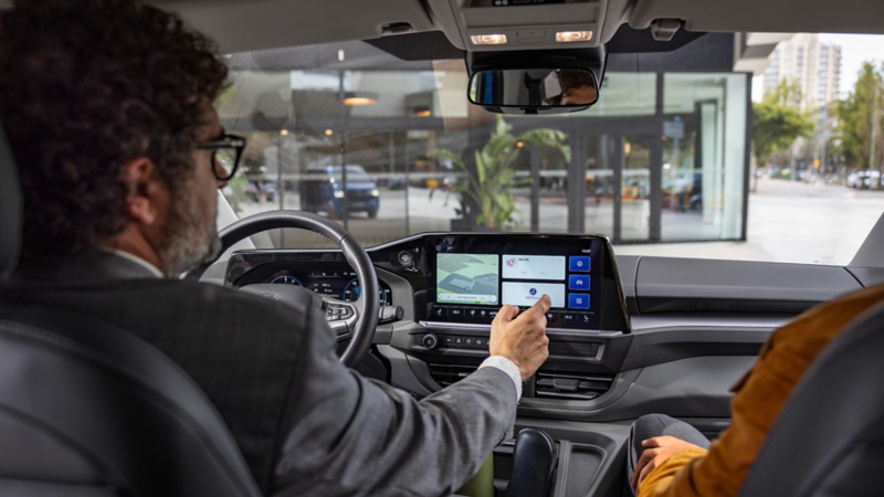 Ein Mann in einem Volkswagen bedient VW Connect Plus.