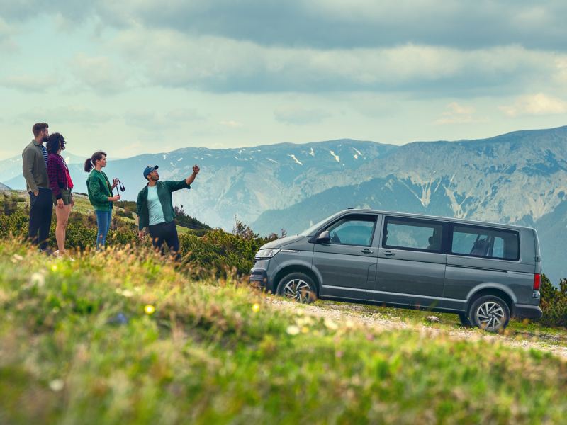 En grupp människor står framför en Volkswagen Caravelle i Alperna.