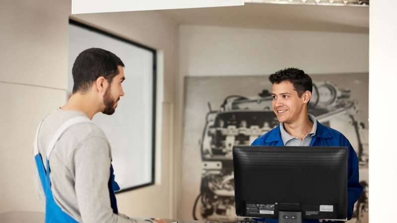 Photo showing two VW technicians talking to each other. 
