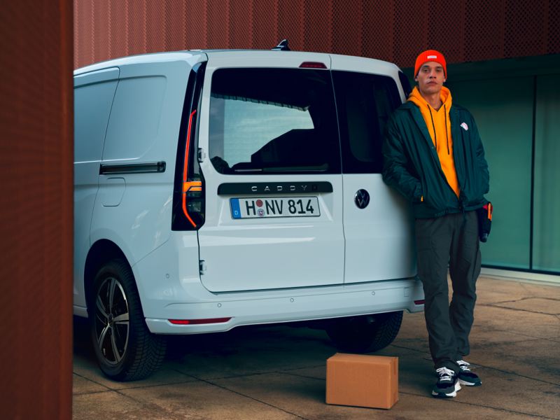 Ein Mann steht vor dem Heck eines VW Caddy Cargo EcoProfi.
