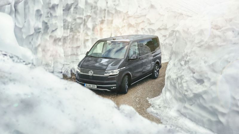 Un Volkswagen California tra due muri di neve mentre affronta una curva.