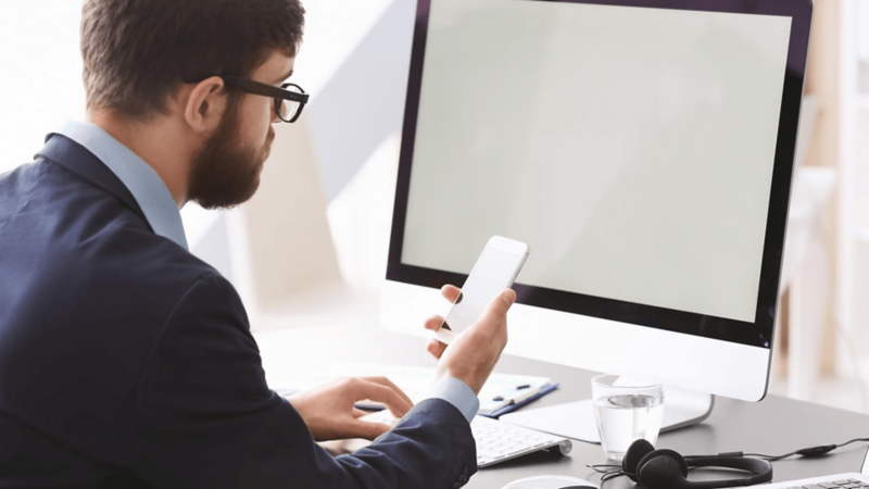 Mężczyzna szuka informacji na komputerze i w telefonie