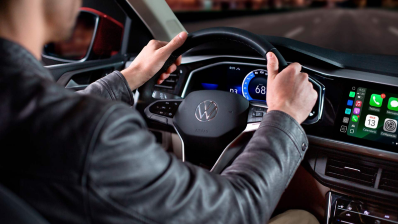 Conductor al volante de un Volkswagen en una vía urbana, con la pantalla multimedia visible.