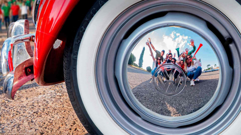 Llanta de un Volkswagen Vocho con aficionados de futbol reflejados en el rin. 