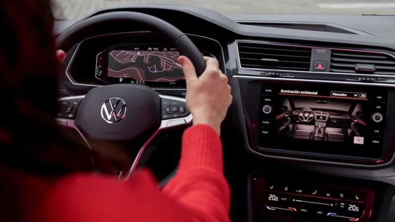 Interior de Volkswagen Tiguan, con Digital Cockpit que muestra ruta, y pantalla táctil que muestra tipo de iluminación. 