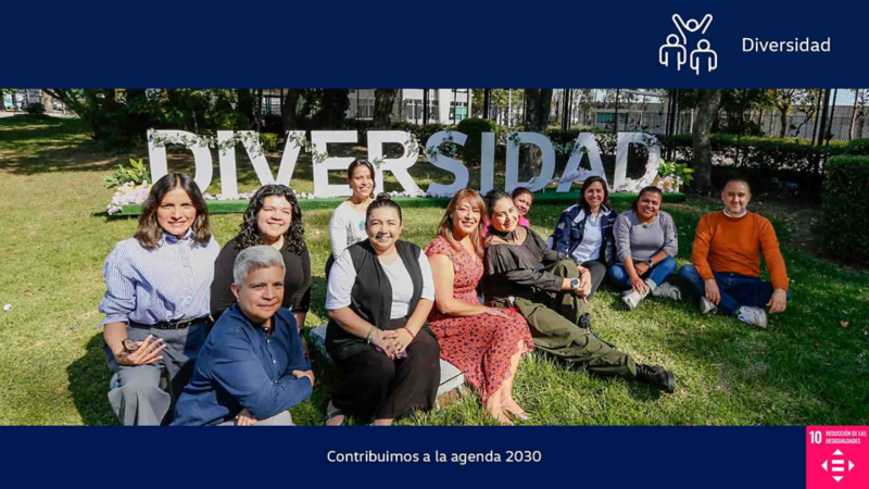 Equipo de Volkswagen posa frente a letrero de Diversidad en jardín.