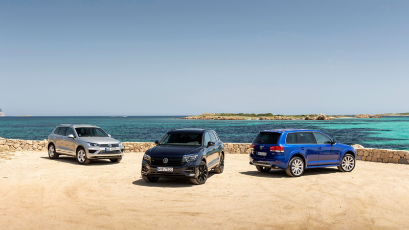 Trois générations du VW Touareg devant une mer turquoise.
