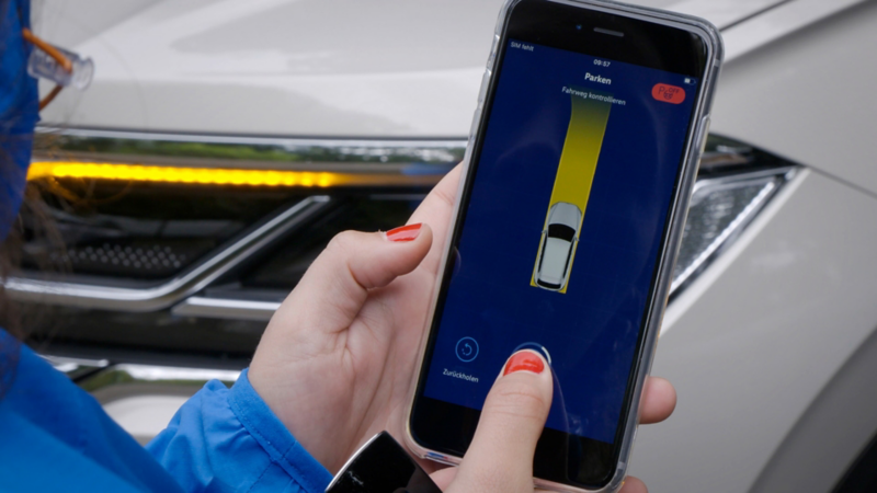 Une personne contrôle un VW Touareg à l’aide d’une application smartphone.