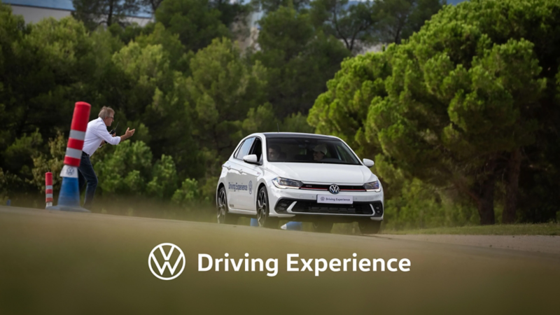 Un hombre animando el paso de un Volkswagen blanco
