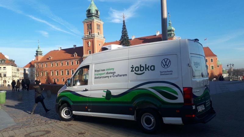 Volkswagen e-Crafter w barwach Żabki stoi na Placu Zamkowym w Warszawie.  