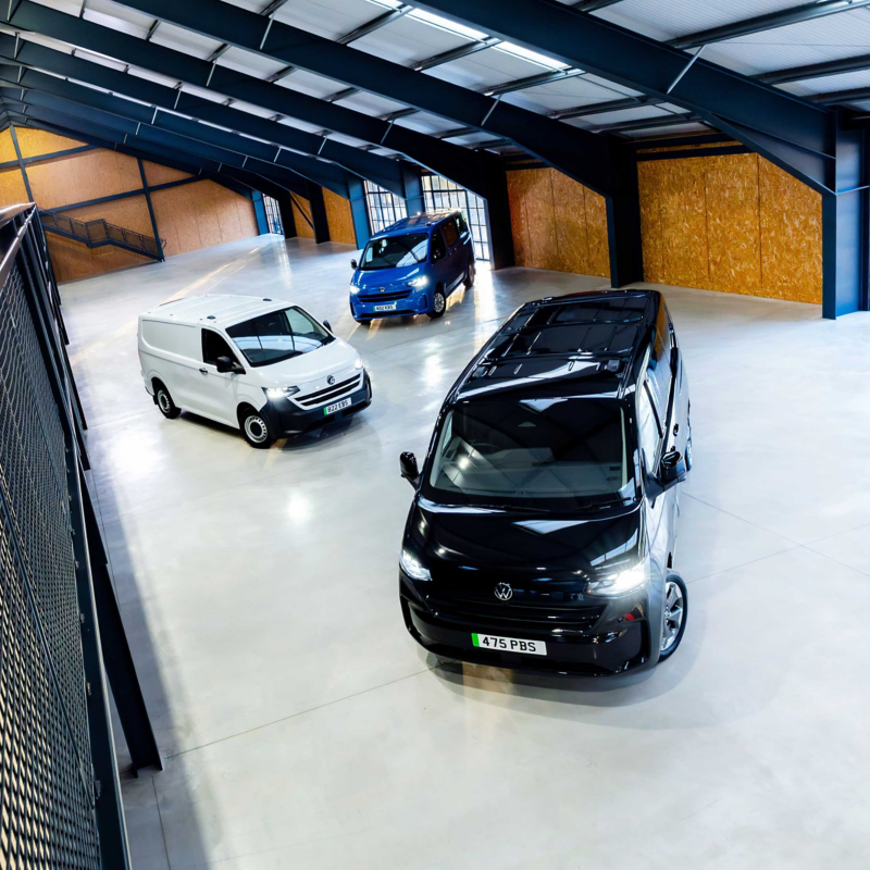 A VW e-Transporter Panel van, e-Transporter Kombi and an e-Transporter Shuttle all parked on a warehouse floor
