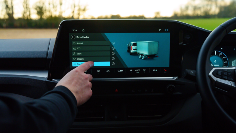 Interior view of a e-Transporter cockpit with a person selecting the Tow option of the Driving Modes on the touchscreen