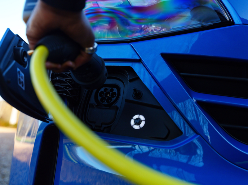 A person putting a charging cord in the sucket of an e-Transporter Shuttle